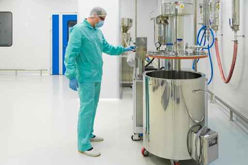Pharmaceutical factory man working with control panel in sterile working conditions wearing protective clothing